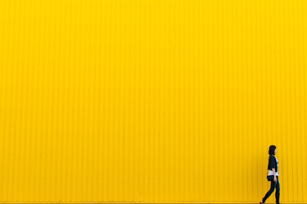 A woman walking next to a yellow wall - How to Set, Track and Achieve Your Business Goals in 2017